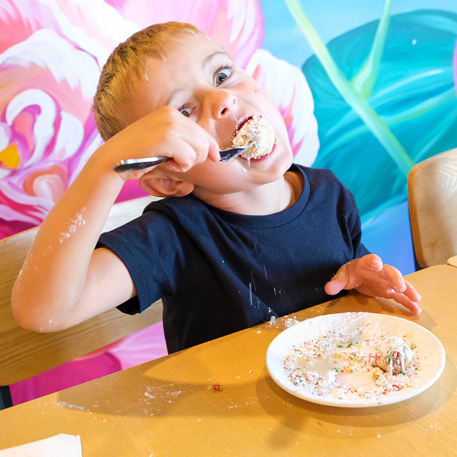 DoughBalls Pizza Restaurant Adelaide homepage image of little boy eating a mouthfull of delicious Doughballs desert.